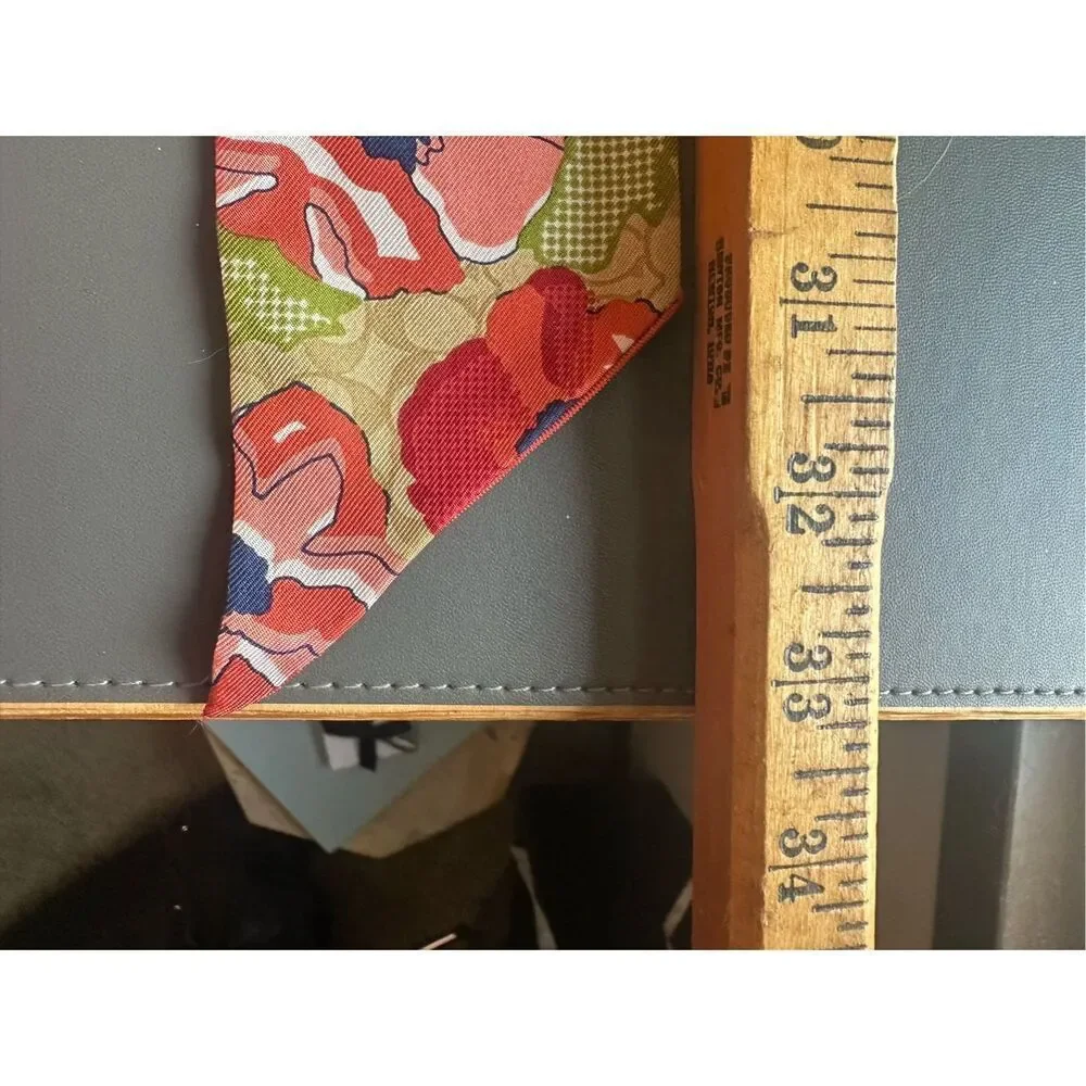 COACH silk twilly scarf orange poppy and tan signature Cs background